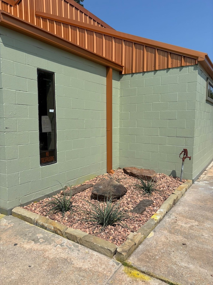 After — Fresh gravel and plantings installed along the same wall
